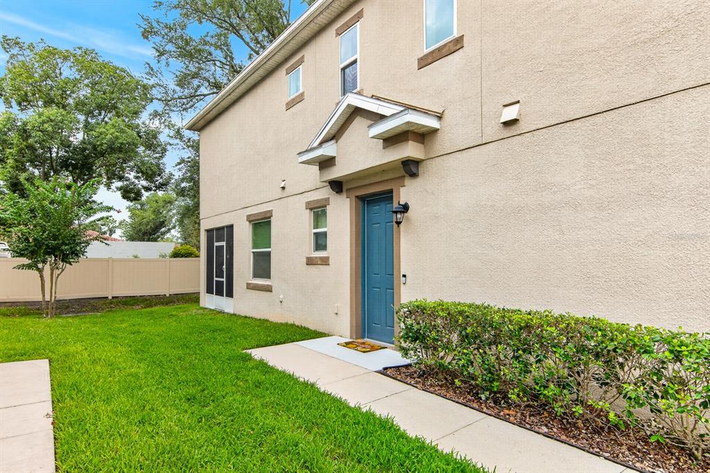 A two-story beige stucco house features a blue front door and a small grassy yard — 6717 CITRUS CREEK LANE, TAMPA, FL