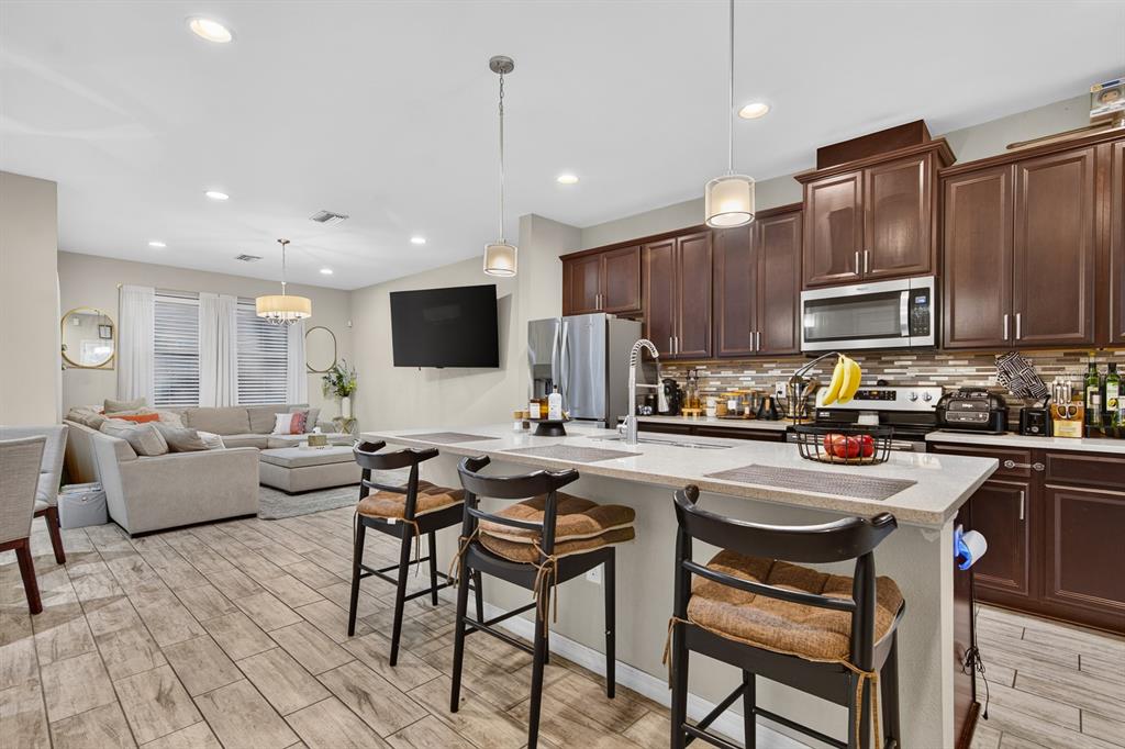 A kitchen with dark wood cabinets and a large island overlooks an open-concept living area — 6717 CITRUS CREEK LANE, TAMPA, FL