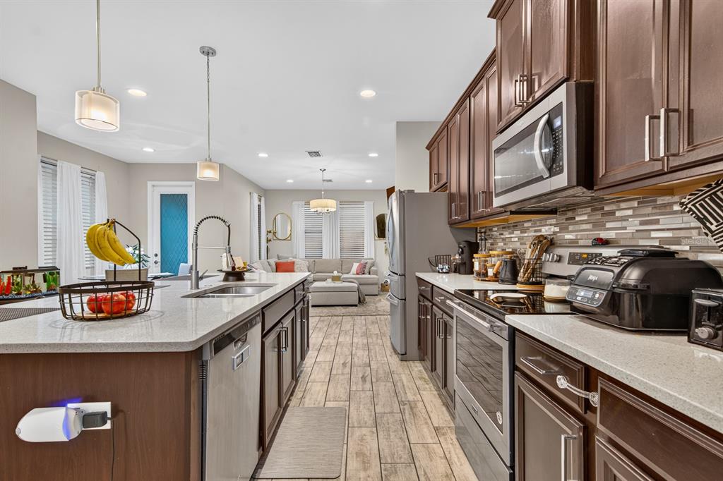 A kitchen with dark wood cabinets, granite countertops, and stainless steel appliances overlooks a living room — 6717 CITRUS CREEK LANE, TAMPA, FL