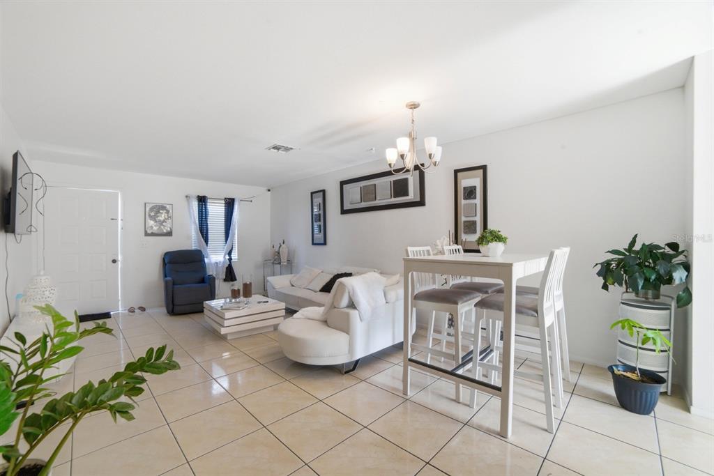 A living and dining area features white tile floors, a white sofa, and a table — 2 E LAS PALMAS WAY, KISSIMMEE, FL
