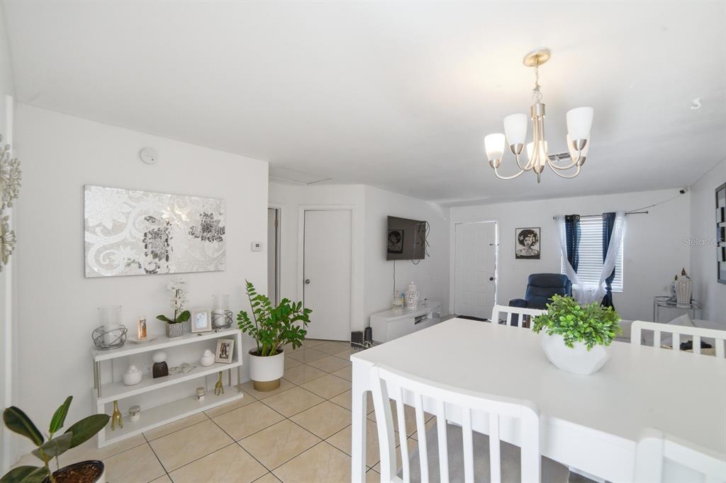 A bright dining area features white furniture, tiled floors, and a chandelier under a ceiling — 2 E LAS PALMAS WAY, KISSIMMEE, FL