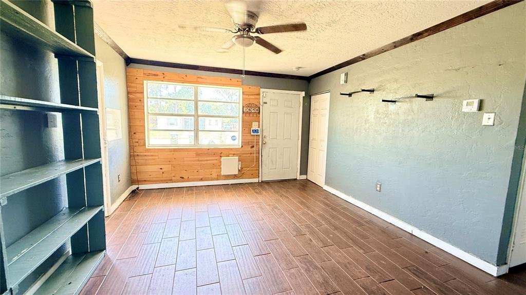 A room with wood-look tile flooring, a wood-paneled accent wall, and a ceiling fan — 4448 CHICOPA STREET, NORTH PORT, FL