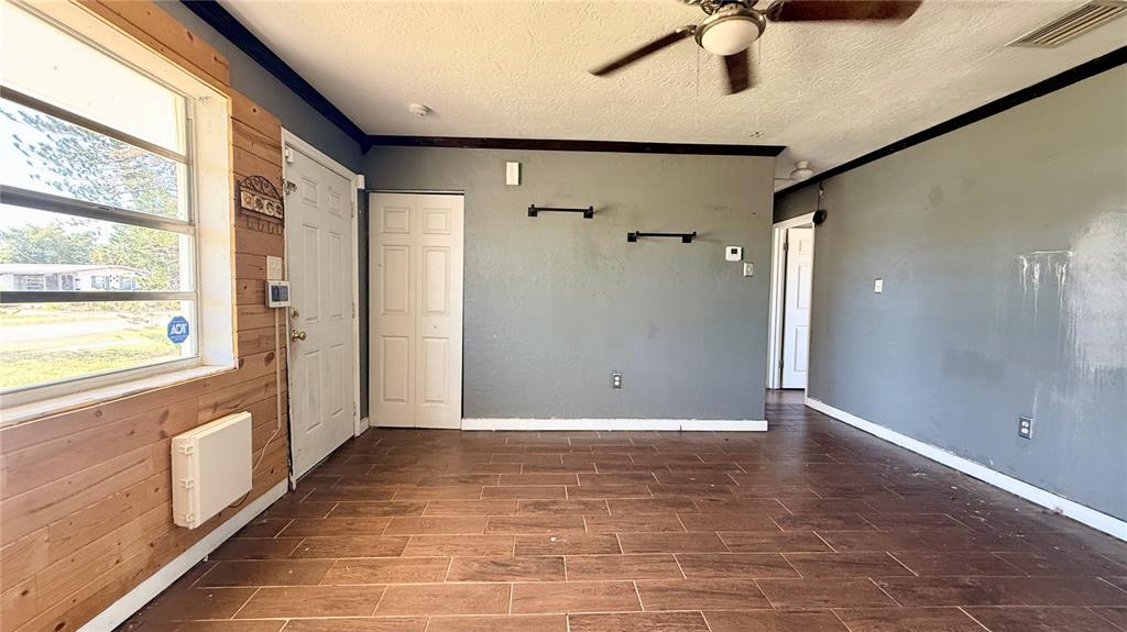 An empty living room features gray walls, wood-look tile flooring, and a ceiling fan — 4448 CHICOPA STREET, NORTH PORT, FL