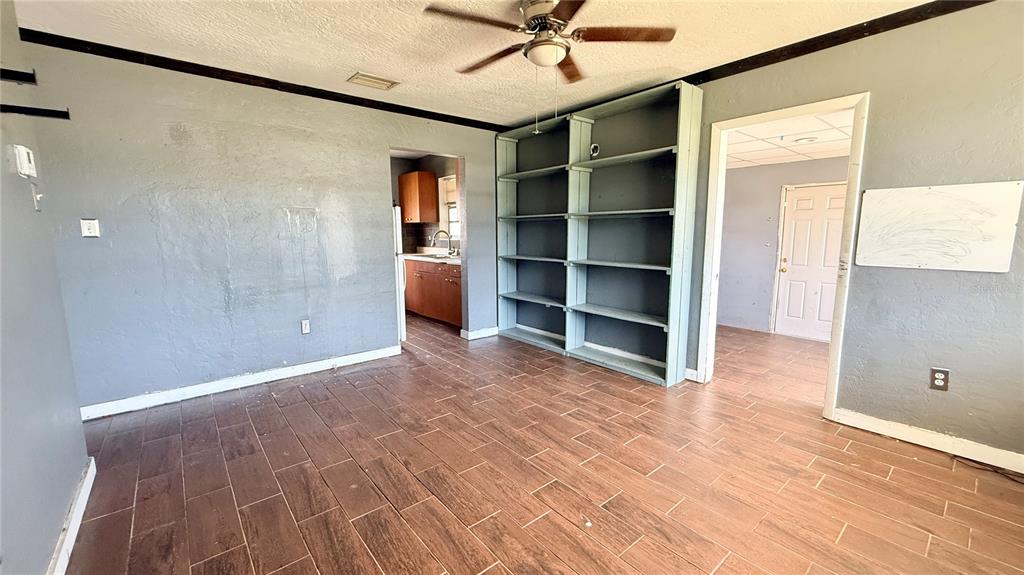 A room with dark gray walls, wood-look tile flooring, built-in shelving, and a ceiling fan — 4448 CHICOPA STREET, NORTH PORT, FL