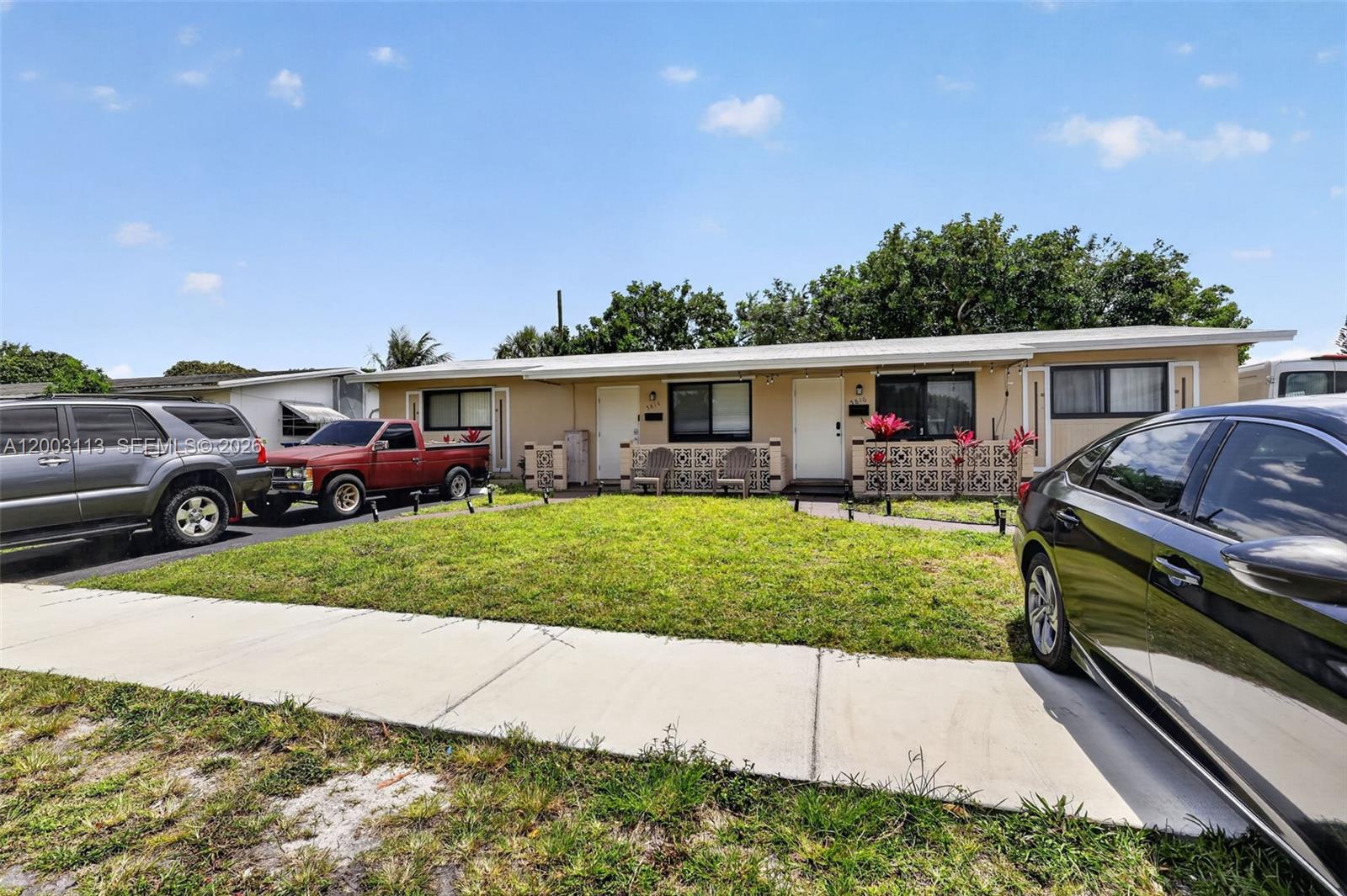 A single-story duplex with a front lawn, driveway, and parked vehicles under a blue sky — 5814 Cleveland St, Hollywood FL 33021, HOLLYWOOD, FL