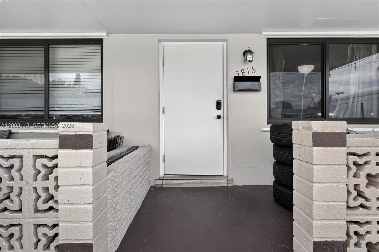 A white front door is centered between two windows and decorative concrete block walls — 5814 Cleveland St, Hollywood FL 33021, HOLLYWOOD, FL
