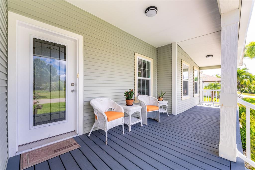 A covered front porch features gray decking, light green siding, and two white wicker chairs — 308 W GRACE STREET, PUNTA GORDA, FL