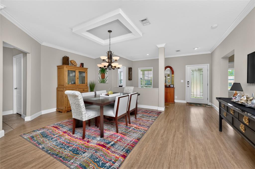A dining room features a wooden table, patterned rug, chandelier, and light wood flooring — 308 W GRACE STREET, PUNTA GORDA, FL