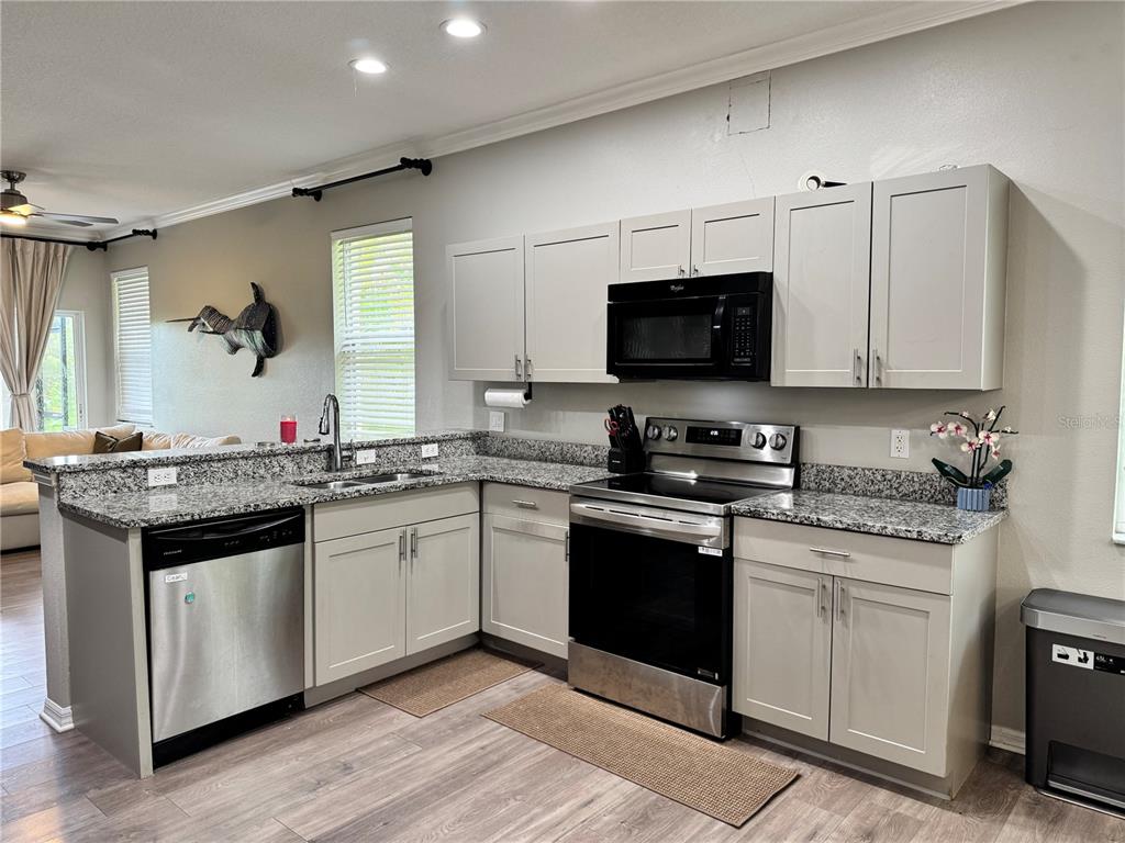 A kitchen features light gray cabinets, granite countertops, stainless steel appliances, and wood-look flooring — 14331 GNATCATCHER TERRACE, BRADENTON, FL