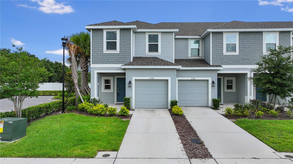 A two-story townhouse with gray siding, shingle roofs, and two attached garages — 4790 REVOLUTIONARY WAY, ST CLOUD, FL