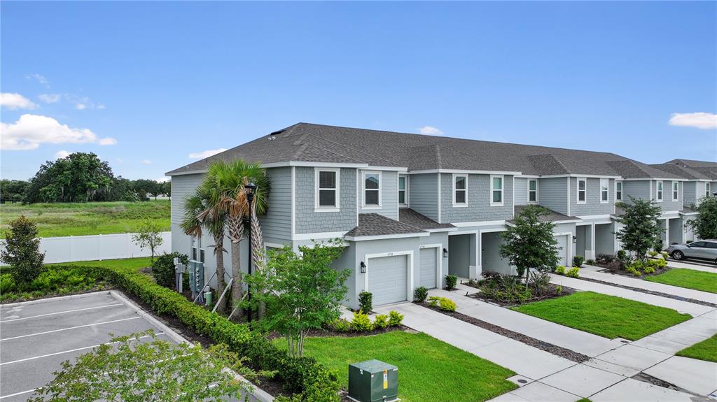 An exterior view of a multi-unit townhouse building with gray siding and attached garages — 4790 REVOLUTIONARY WAY, ST CLOUD, FL
