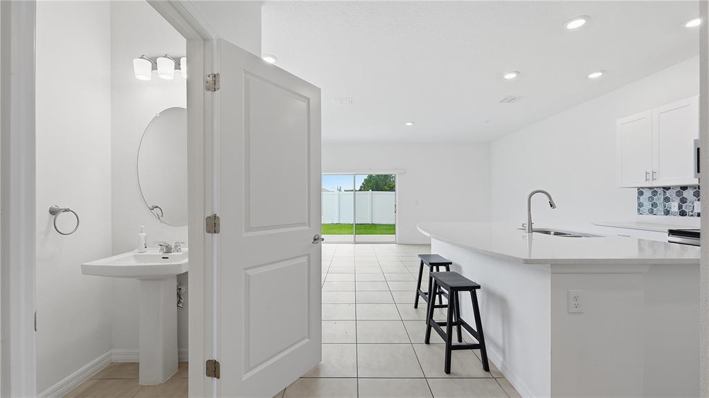 A view from a powder room looking into an open-concept kitchen and living area — 4790 REVOLUTIONARY WAY, ST CLOUD, FL