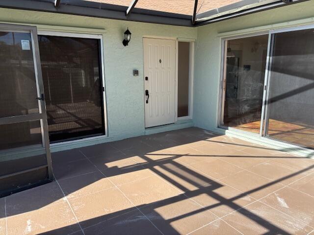 A covered patio features tiled flooring, a white entry door, and two sliding glass doors — 101 Harvest Moon Court # C, Jupiter FL 33458, JUPITER, FL