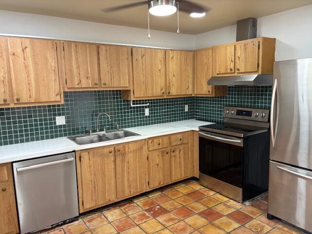 A kitchen features oak cabinets, a green tiled backsplash, stainless steel appliances, and terracotta flooring — 101 Harvest Moon Court # C, Jupiter FL 33458, JUPITER, FL