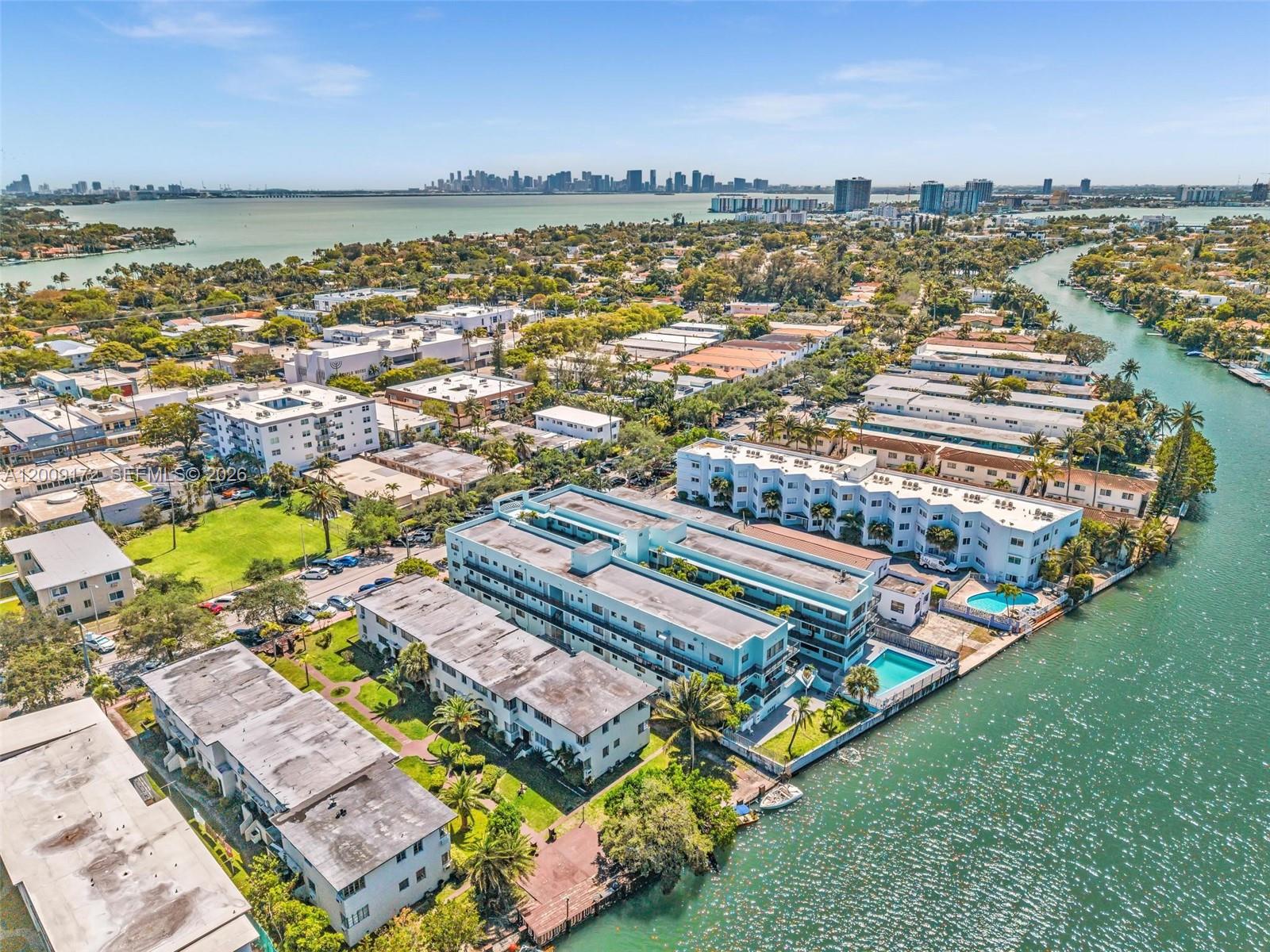 An aerial view shows multi-story apartment buildings situated along a canal near the ocean — 1165 Marseille Dr # 19, Miami Beach FL 33141, MIAMI BEACH, FL