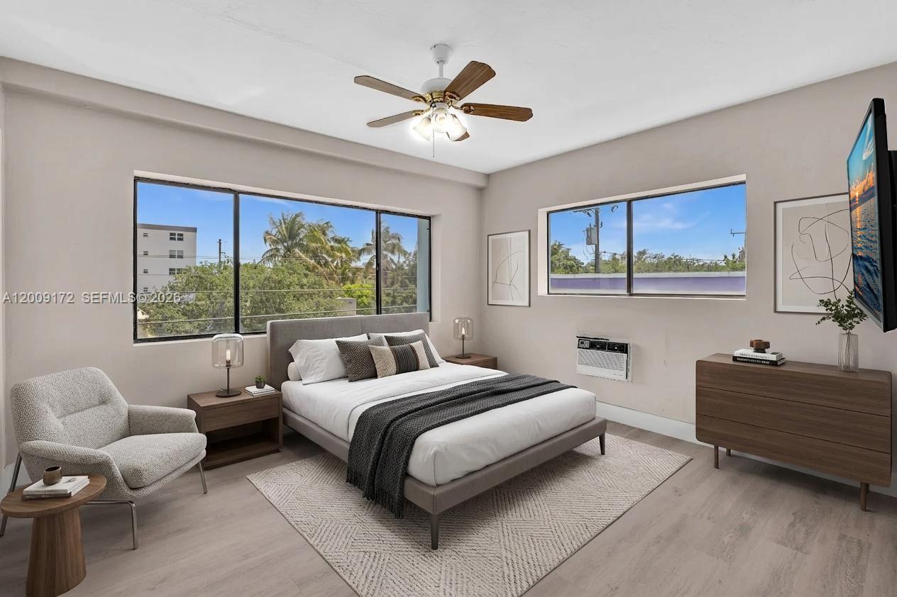 A bedroom features a bed, armchair, dresser, ceiling fan, and windows with an exterior view — 1165 Marseille Dr # 19, Miami Beach FL 33141, MIAMI BEACH, FL