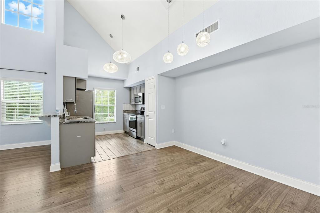 A kitchen and dining area with vaulted ceilings, gray cabinetry, and wood-look flooring — 9368 LAKE CHASE ISLAND WAY UNIT 9368, TAMPA, FL