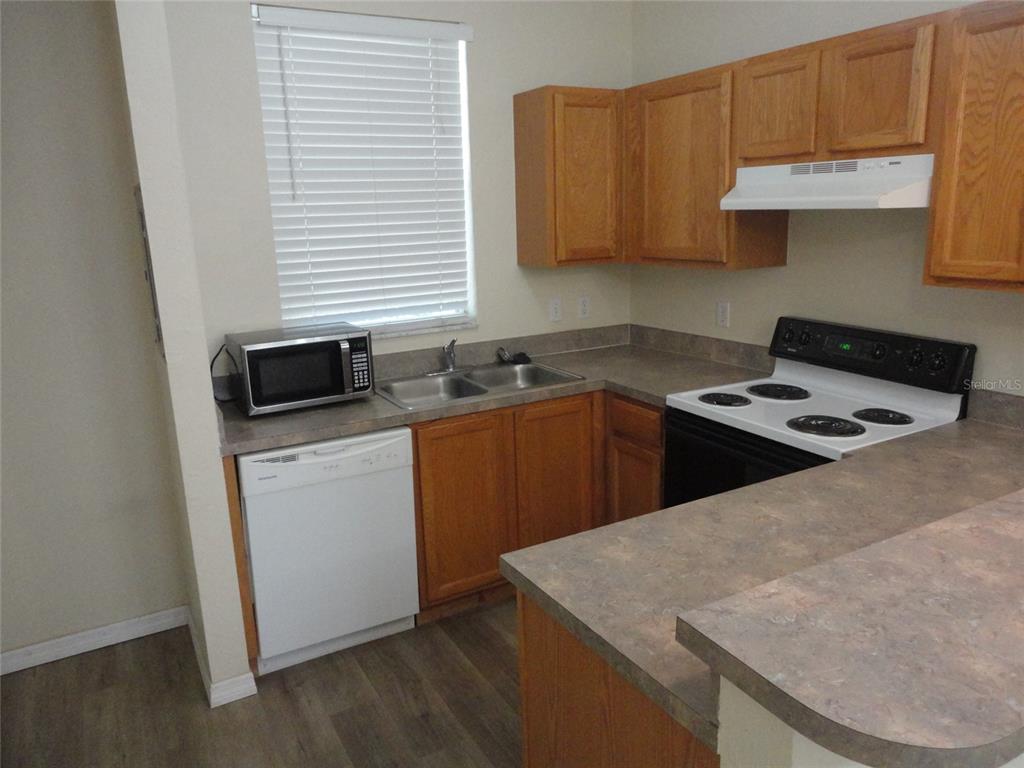 A kitchen features wood cabinets, laminate countertops, a white dishwasher, and a black electric stove — 3584 SW 30TH WAY UNIT 129, GAINESVILLE, FL