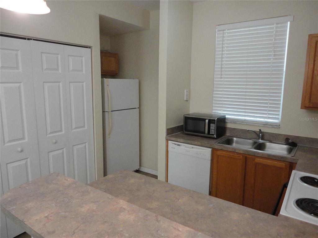 A kitchen features white appliances, wood cabinets, a double sink, and a laminate countertop — 3584 SW 30TH WAY UNIT 129, GAINESVILLE, FL