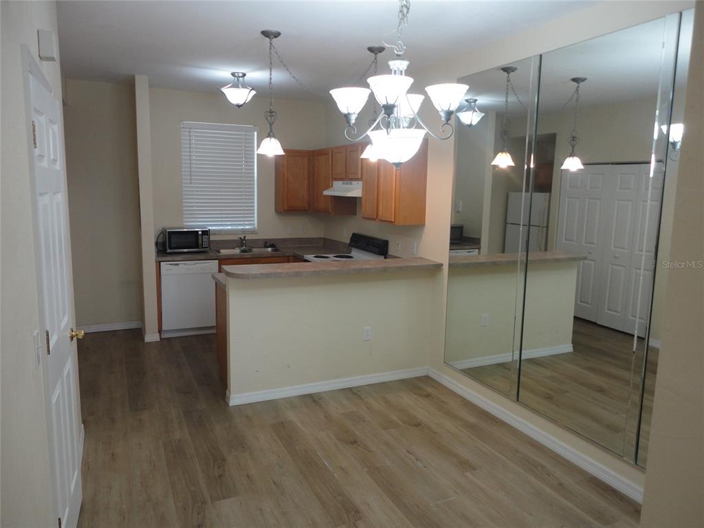 A kitchen with wood cabinets, a breakfast bar, and a mirrored wall in the dining area — 3584 SW 30TH WAY UNIT 129, GAINESVILLE, FL
