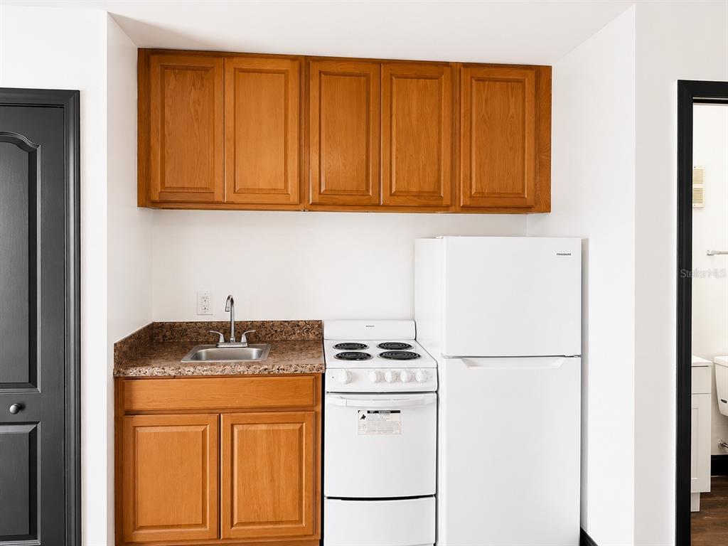 A small kitchen area features wooden cabinets, a sink, a white stove, and a refrigerator — 2795 L B MCLEOD ROAD UNIT A, ORLANDO, FL