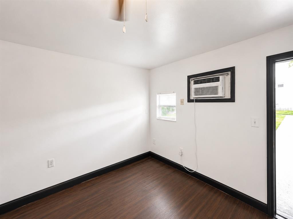 A small, empty room with white walls, dark trim, wood-look flooring, and a window air conditioner — 2795 L B MCLEOD ROAD UNIT A, ORLANDO, FL