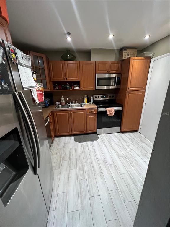 A kitchen features wood cabinets, stainless steel appliances, and light-colored wood-look tile flooring — 5961 N FALLS CIRCLE DRIVE UNIT 411, LAUDERHILL, FL