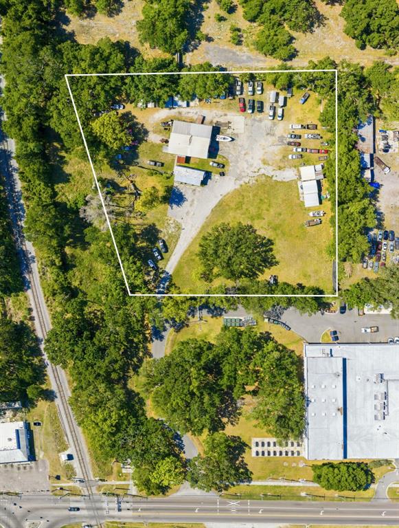 An aerial view shows a fenced industrial lot with several buildings and parked vehicles — 2415 E SLIGH AVENUE, TAMPA, FL