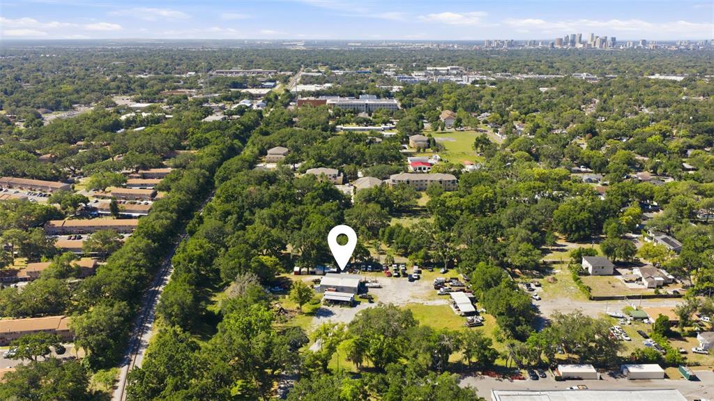 An aerial view shows a commercial property with a warehouse and parking lot amidst trees — 2415 E SLIGH AVENUE, TAMPA, FL