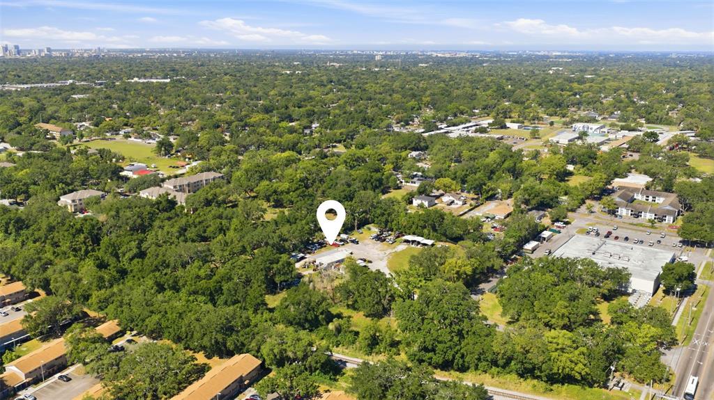 An aerial view shows a commercial property with a parking lot surrounded by dense trees — 2415 E SLIGH AVENUE, TAMPA, FL