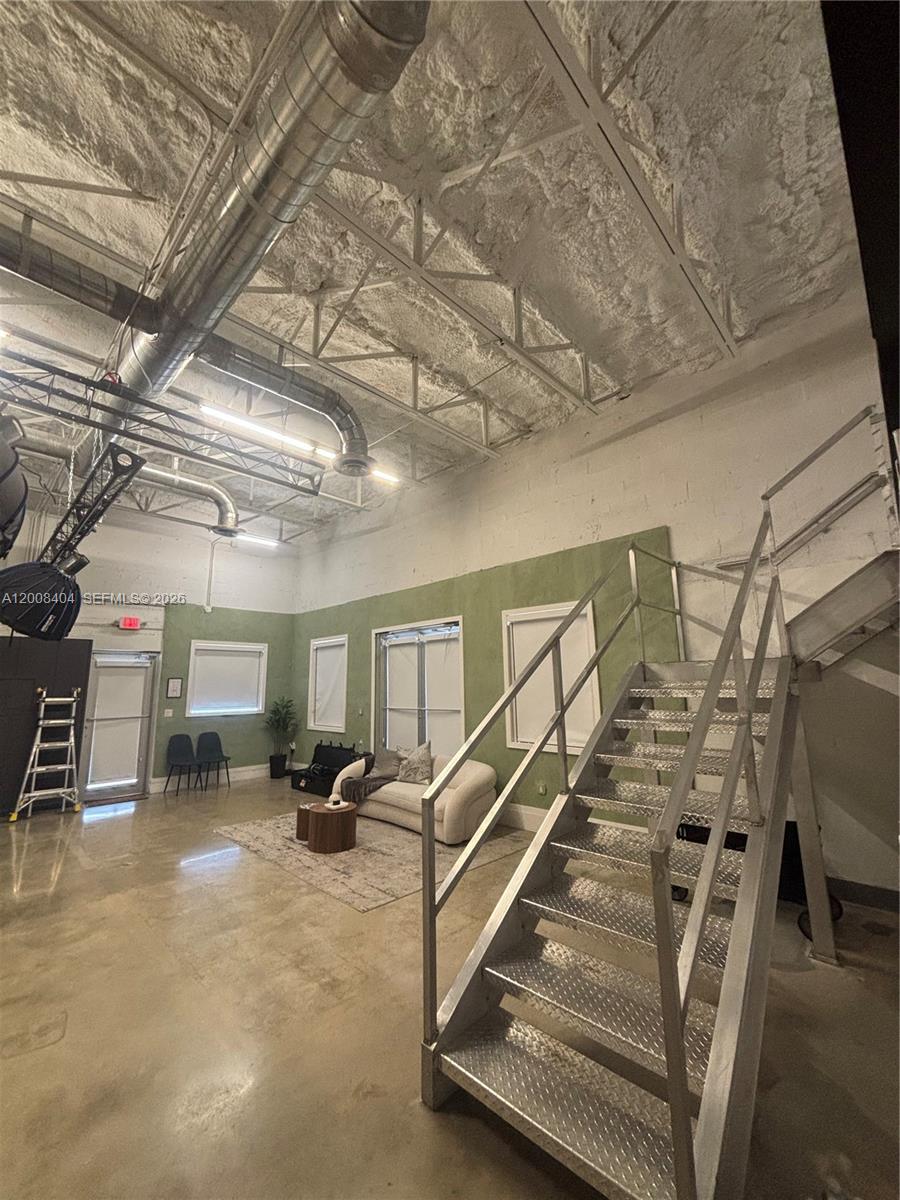 An industrial-style room features exposed ductwork, a high ceiling with spray insulation, and metal stairs — 1050 E 17th St, Hialeah FL 33010, HIALEAH, FL
