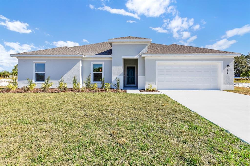 A single-story house with a light gray exterior, a two-car garage, and a front entrance — 636 GRAND OAKS DRIVE, AVON PARK, FL