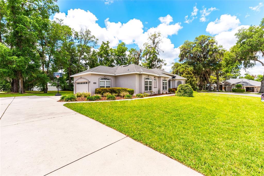 A single-story house with a beige exterior, a concrete driveway, and a large front lawn — 4518 SE 33RD PLACE, OCALA, FL