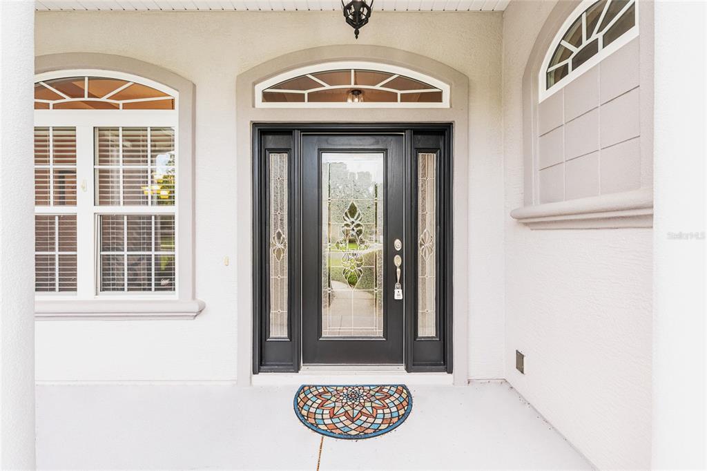 A black front door with glass sidelights and a transom window sits on a porch — 4518 SE 33RD PLACE, OCALA, FL