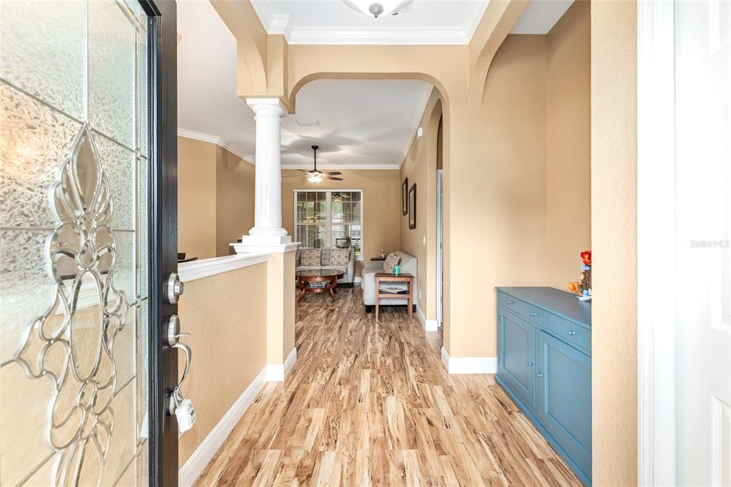 An entryway with wood-look flooring leads into a living area featuring a white column — 4518 SE 33RD PLACE, OCALA, FL