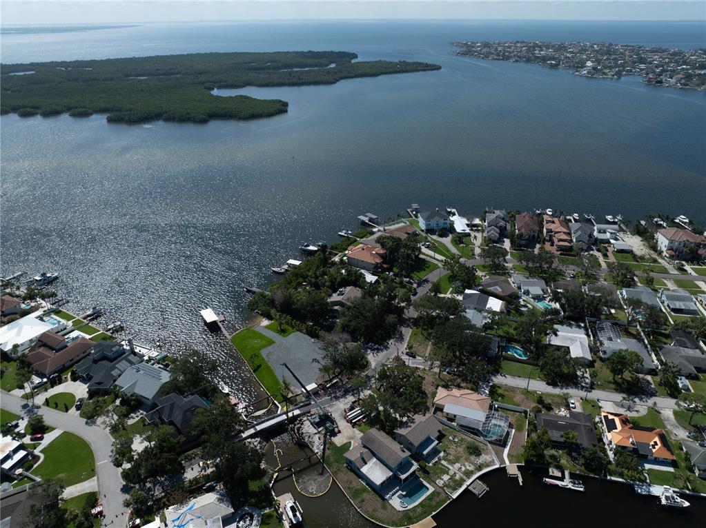 An aerial view shows a coastal residential neighborhood with waterfront homes, docks, and a bridge — 6663 BAYOU GRANDE BOULEVARD NE, ST PETERSBURG, FL
