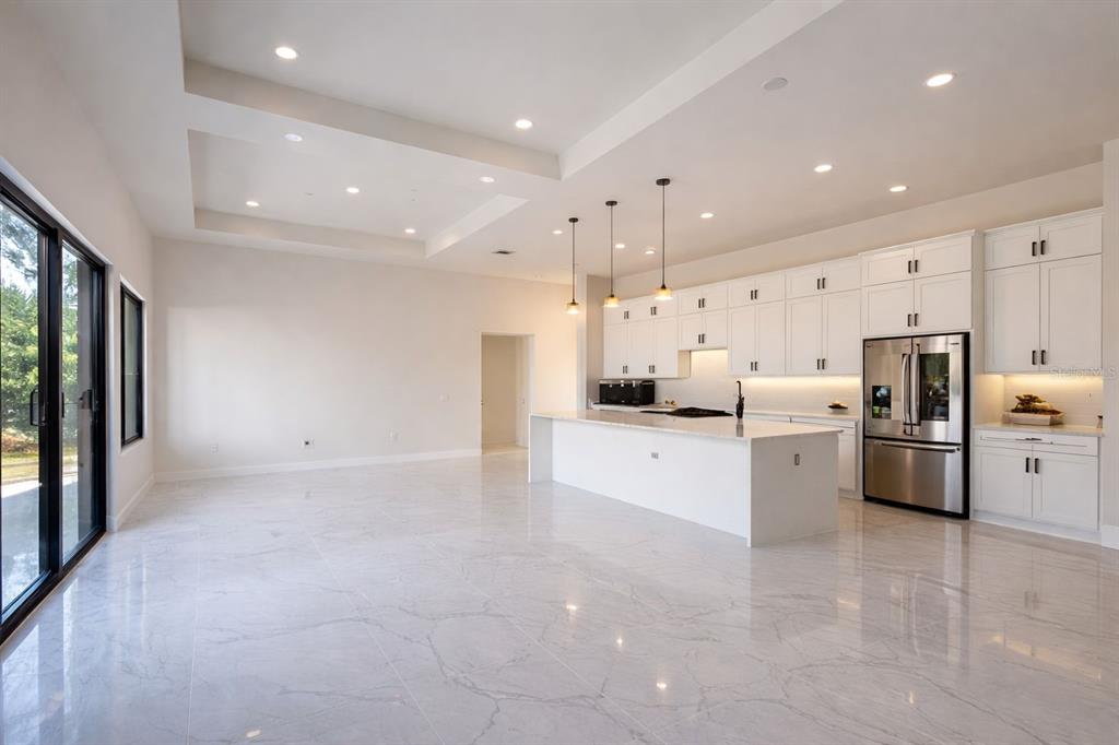 A modern kitchen with white cabinetry, a large island, and marble-style flooring in an open-concept space — 9477 ATTICA CIRCLE, PORT CHARLOTTE, FL