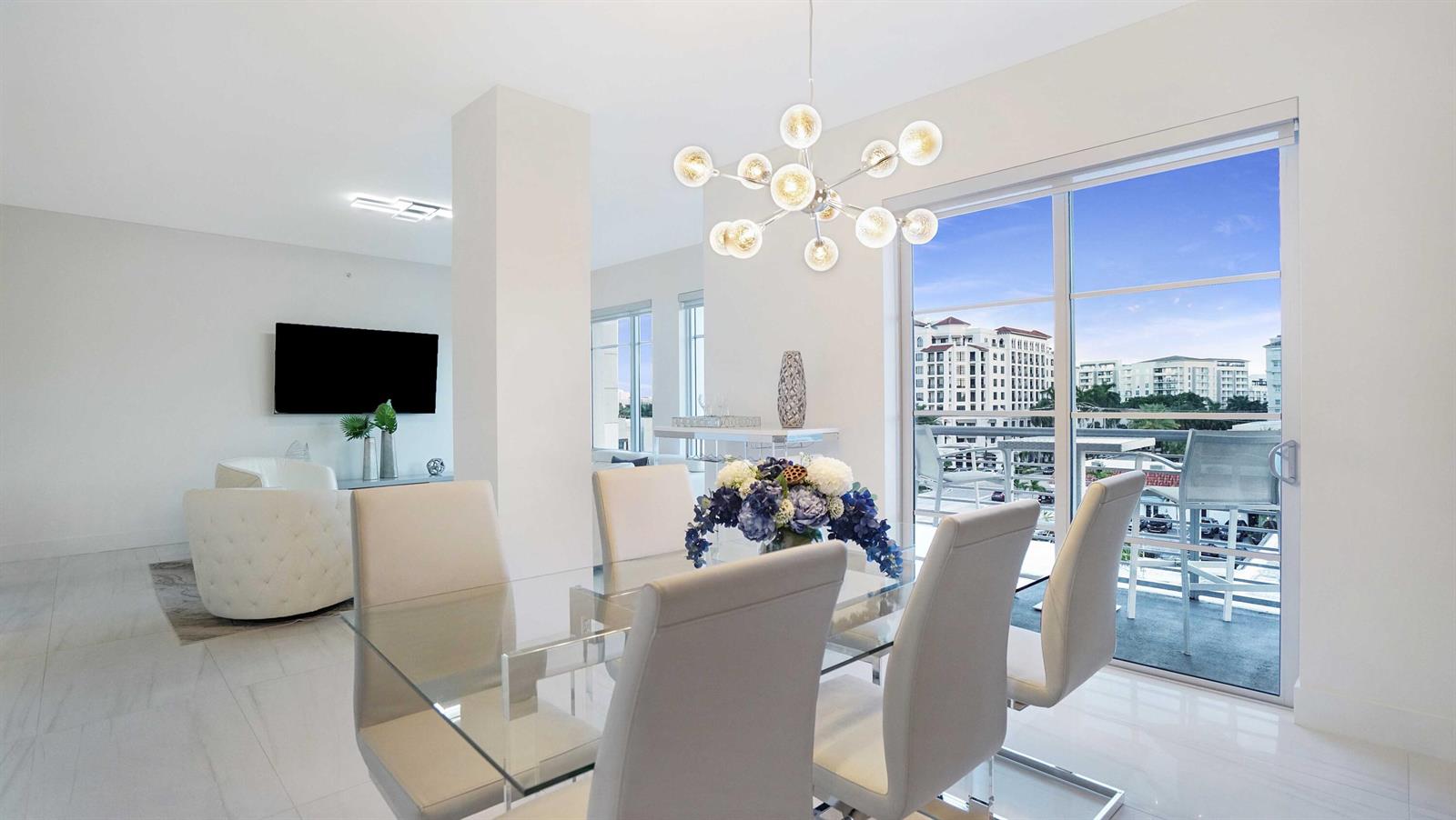 A dining area with a glass table and modern chandelier overlooks a balcony and city — 155 E Boca Raton Road # 501, Boca Raton FL 33432, BOCA RATON, FL