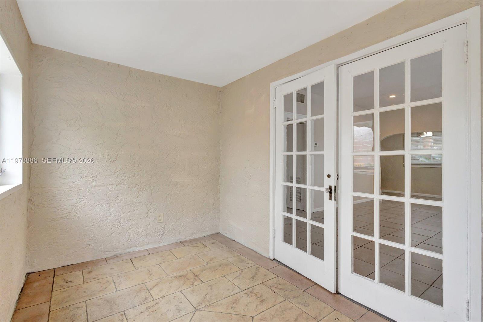 A sunroom features beige textured walls, tiled flooring, and white French doors — 630 33rd St # 0, West Palm Beach FL 33407, WEST PALM BEACH, FL