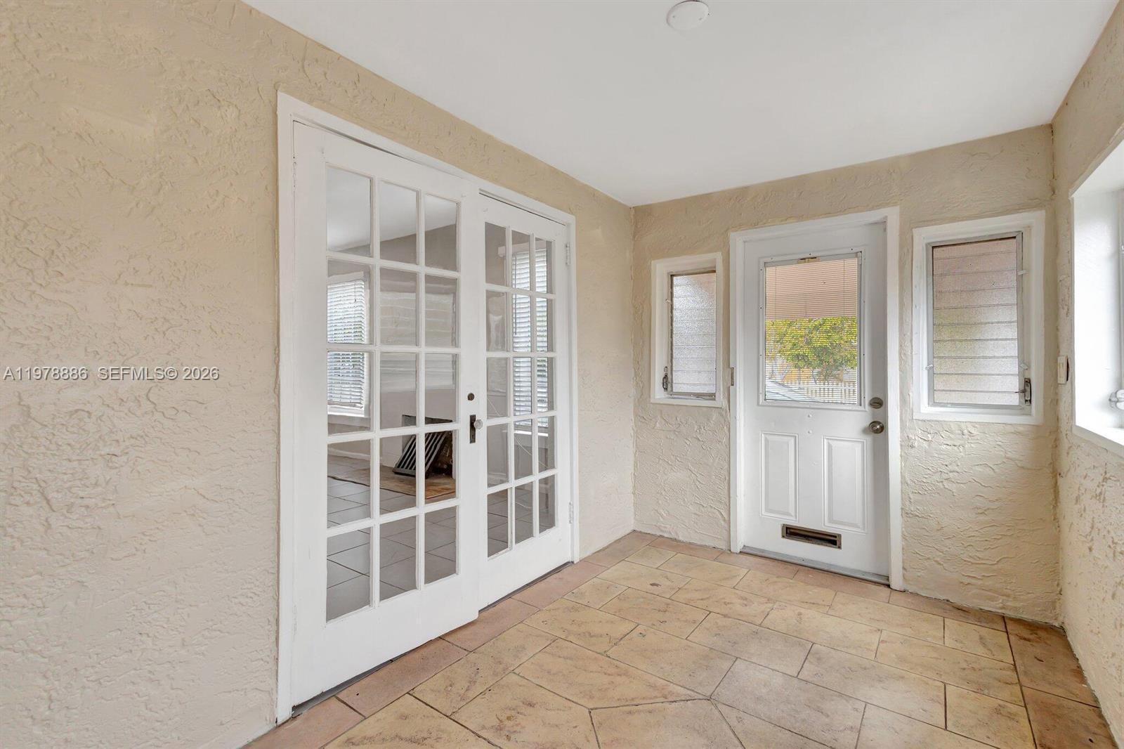 A sunroom features tiled flooring, textured walls, French doors, and a white entry door — 630 33rd St # 0, West Palm Beach FL 33407, WEST PALM BEACH, FL