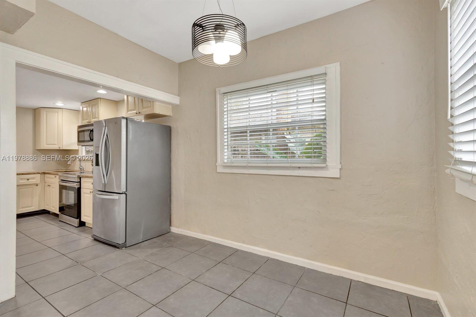 A dining area with gray tile flooring features a modern pendant light and a window — 630 33rd St # 0, West Palm Beach FL 33407, WEST PALM BEACH, FL