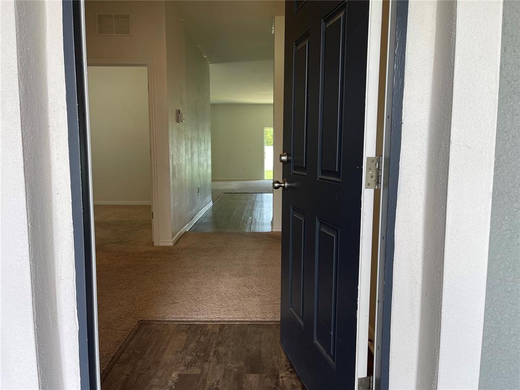 A view through an open dark blue front door into a home with carpeted flooring — 2858 NEVERLAND DRIVE, NEW SMYRNA BEACH, FL