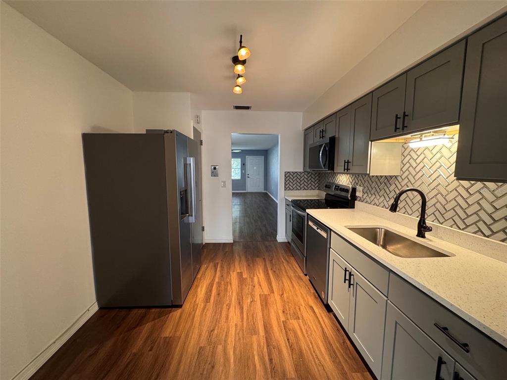 A kitchen features gray cabinets, white countertops, a herringbone backsplash, and stainless steel appliances — 5155 9TH AVENUE N UNIT 104, ST PETERSBURG, FL