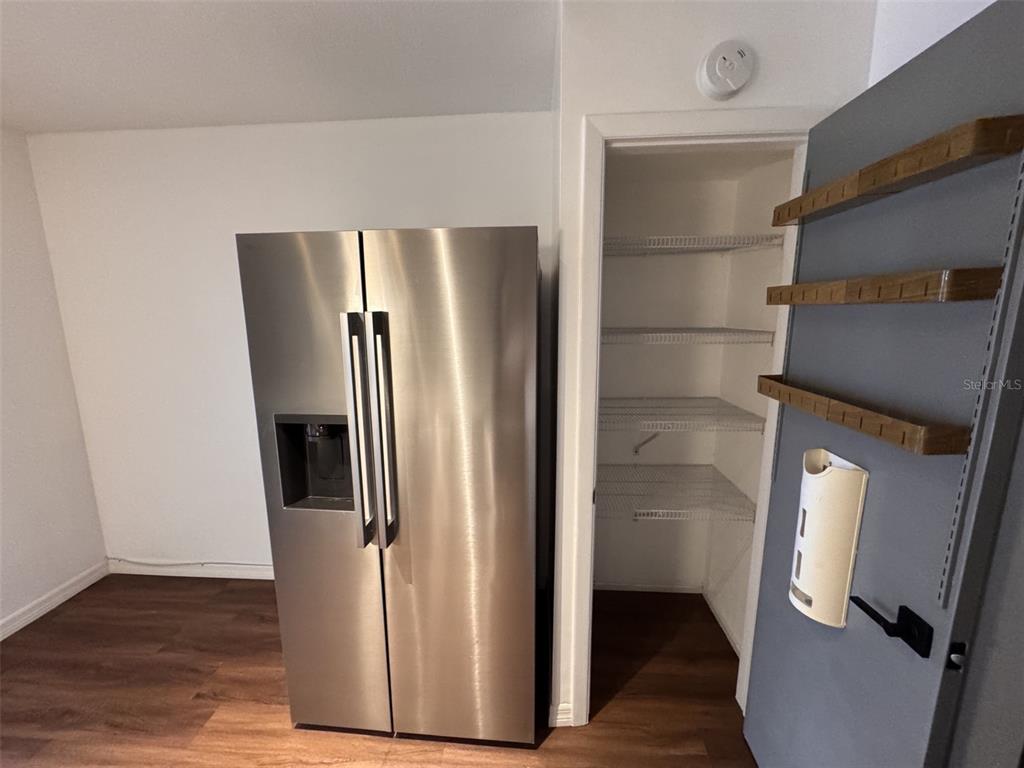 A stainless steel refrigerator stands next to an open pantry with wire shelving — 5155 9TH AVENUE N UNIT 104, ST PETERSBURG, FL