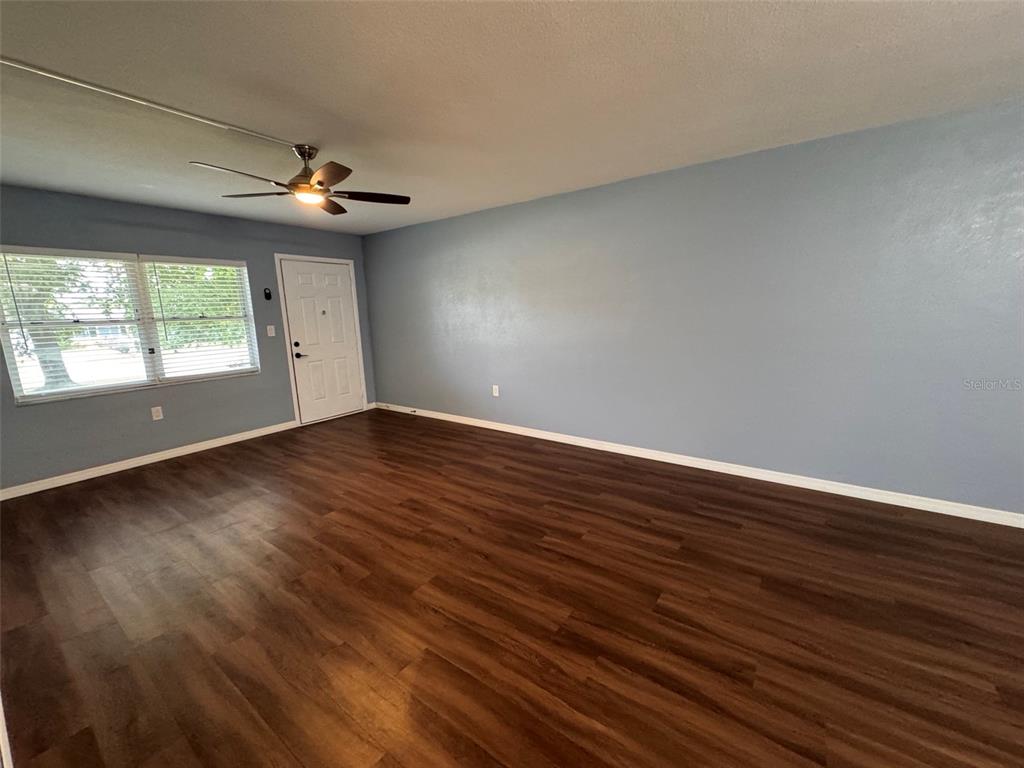An empty room features light blue walls, dark wood-look flooring, and a ceiling fan — 5155 9TH AVENUE N UNIT 104, ST PETERSBURG, FL