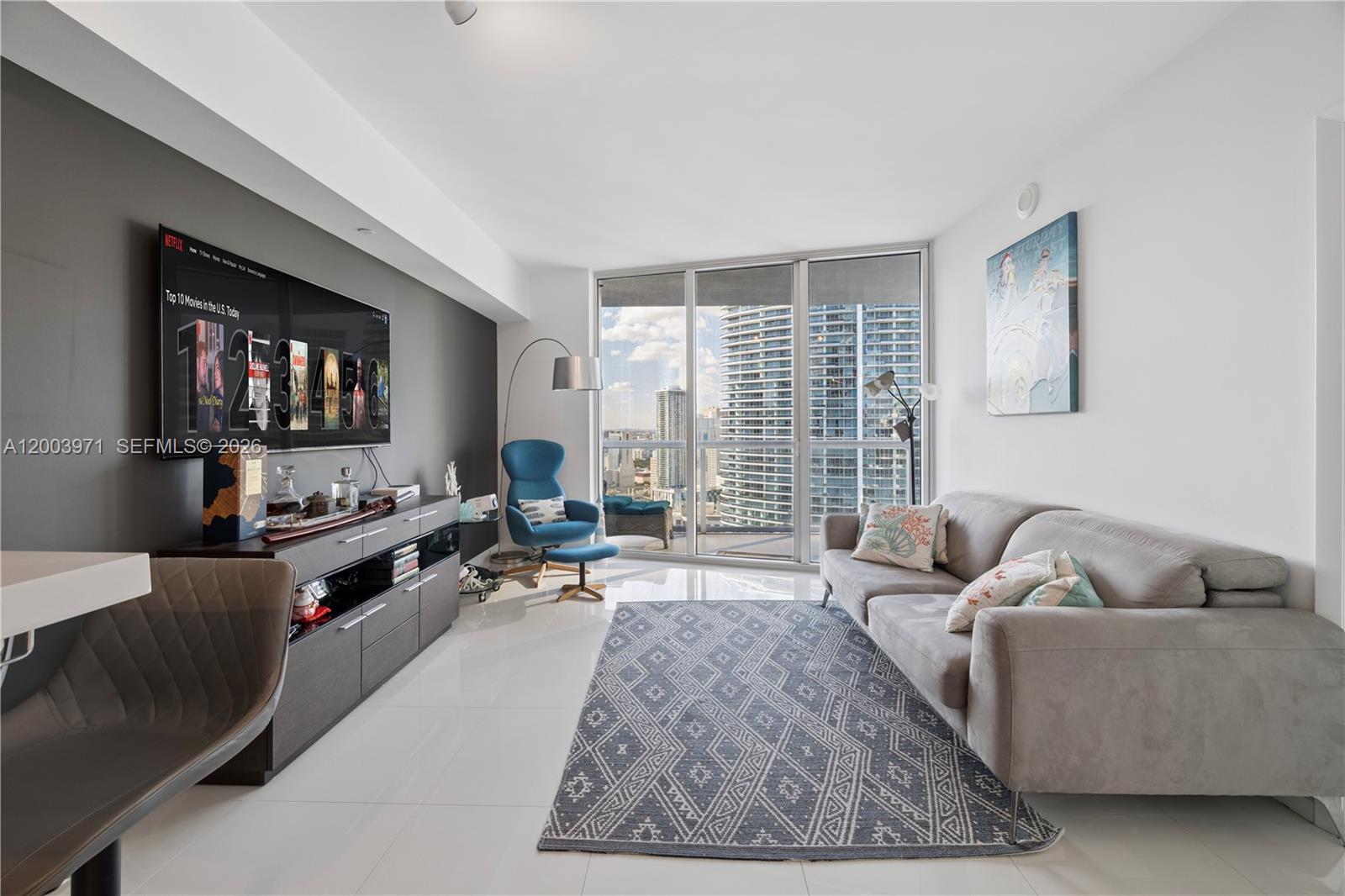 A modern living room features a grey accent wall, a grey sofa, and floor-to-ceiling windows — 465 Brickell Ave # 3804, Miami FL 33131, MIAMI, FL