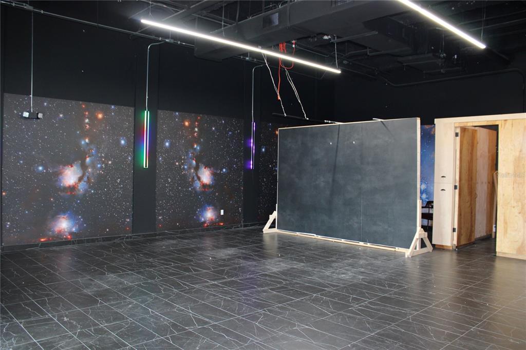 An interior room features dark marble-patterned flooring, space-themed wall panels, and a large freestanding chalkboard — 26489 US HIGHWAY 19 N UNIT 1, CLEARWATER, FL