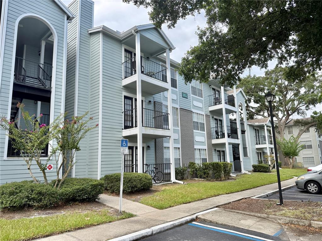 An exterior view of a multi-story apartment building with light blue siding and private balconies — 2550 N ALAFAYA TRAIL UNIT 2209, ORLANDO, FL