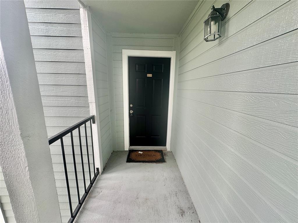 An exterior view of a black front door with a welcome mat on a porch — 2550 N ALAFAYA TRAIL UNIT 2209, ORLANDO, FL