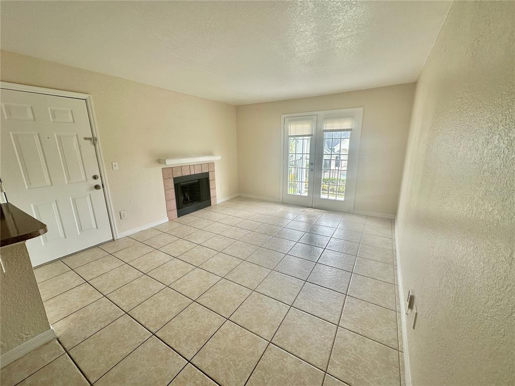 A living room with tile flooring, a fireplace, and glass French doors leading outside — 2550 N ALAFAYA TRAIL UNIT 2209, ORLANDO, FL